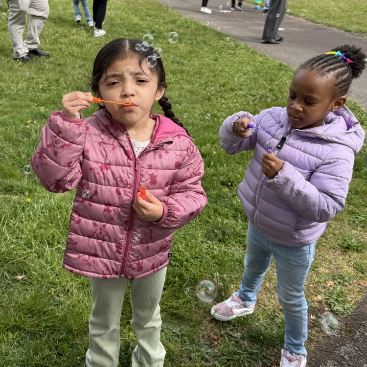 Young students blowing bubbles outside