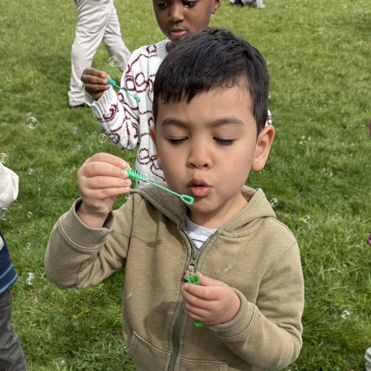 Young students blowing bubbles outside
