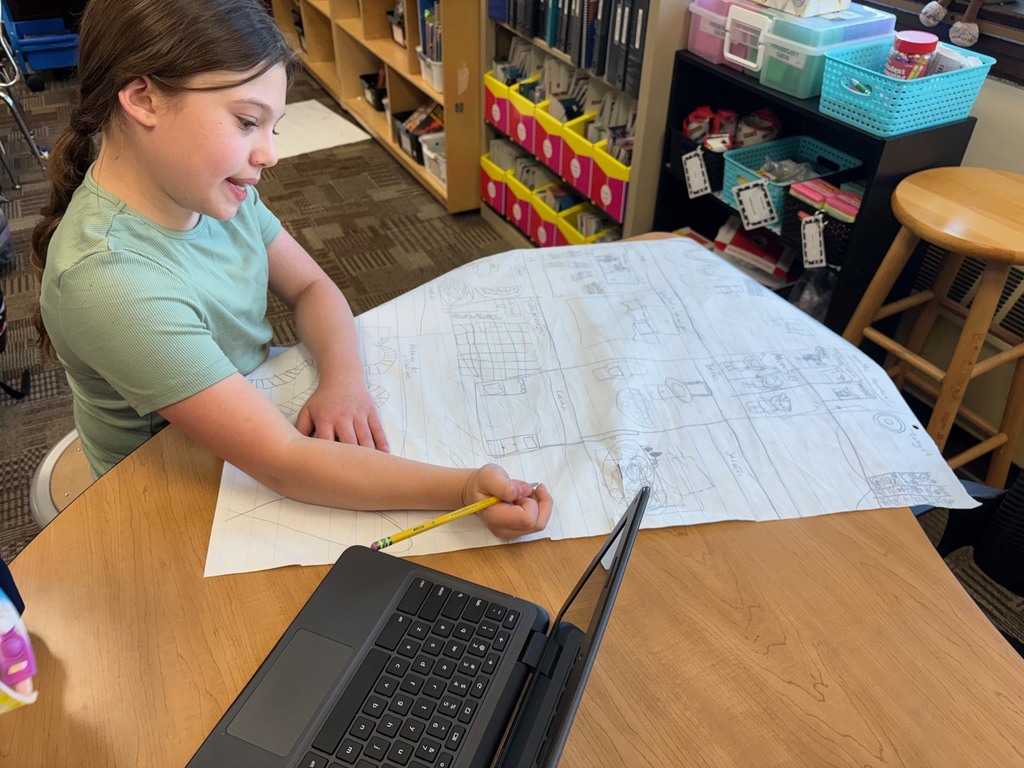 Student working on a poster drawing of a house