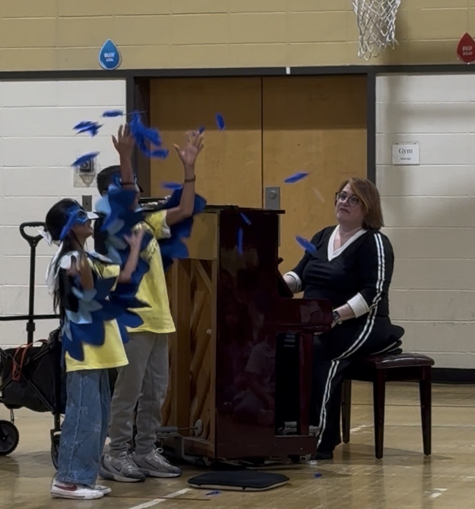 Students pretending to be birds by a piano
