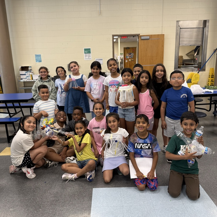 4th graders holding up their science art projects