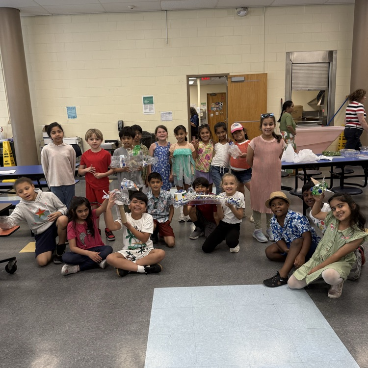 4th graders holding up their science art projects