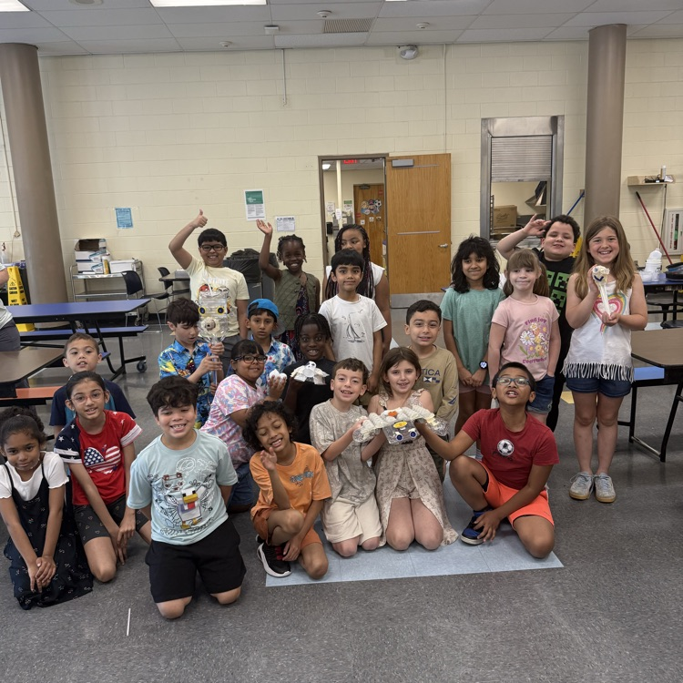4th graders holding up their science art projects