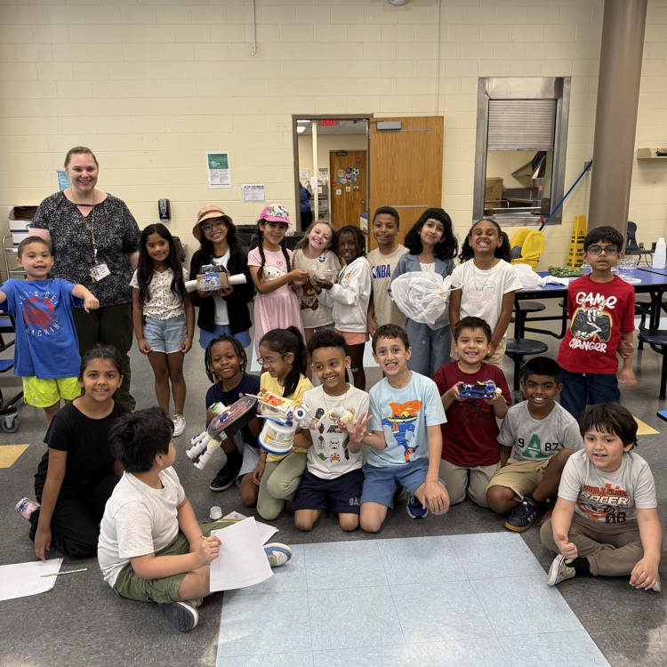 4th graders holding up their science art projects