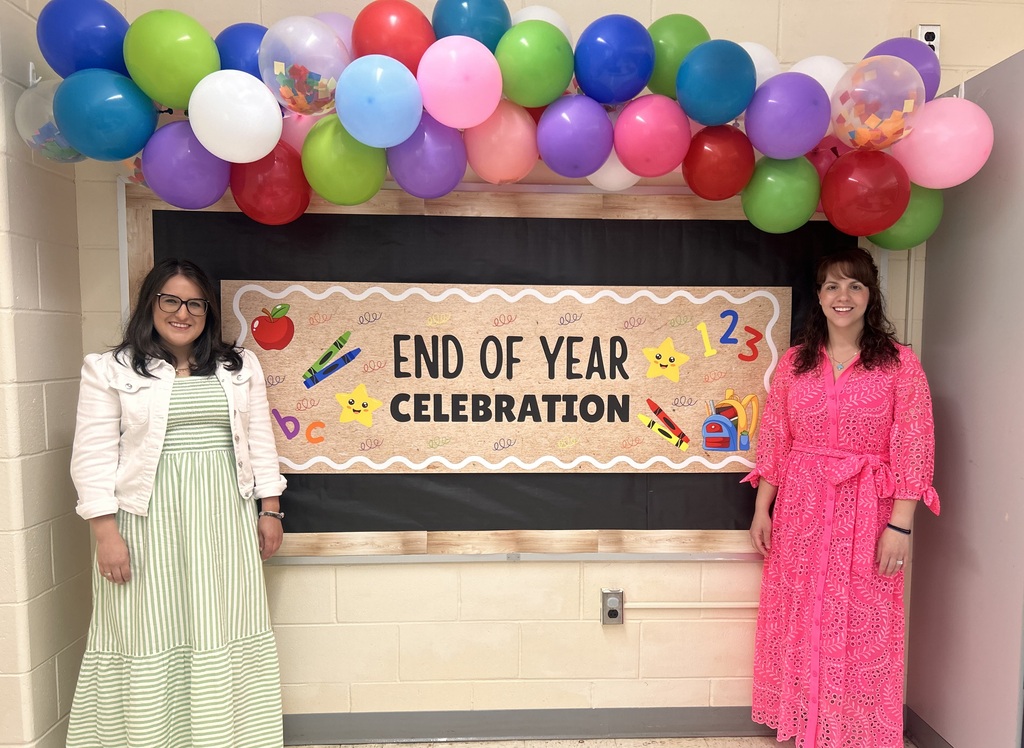 Two teachers in front of an end of year sign with balloons