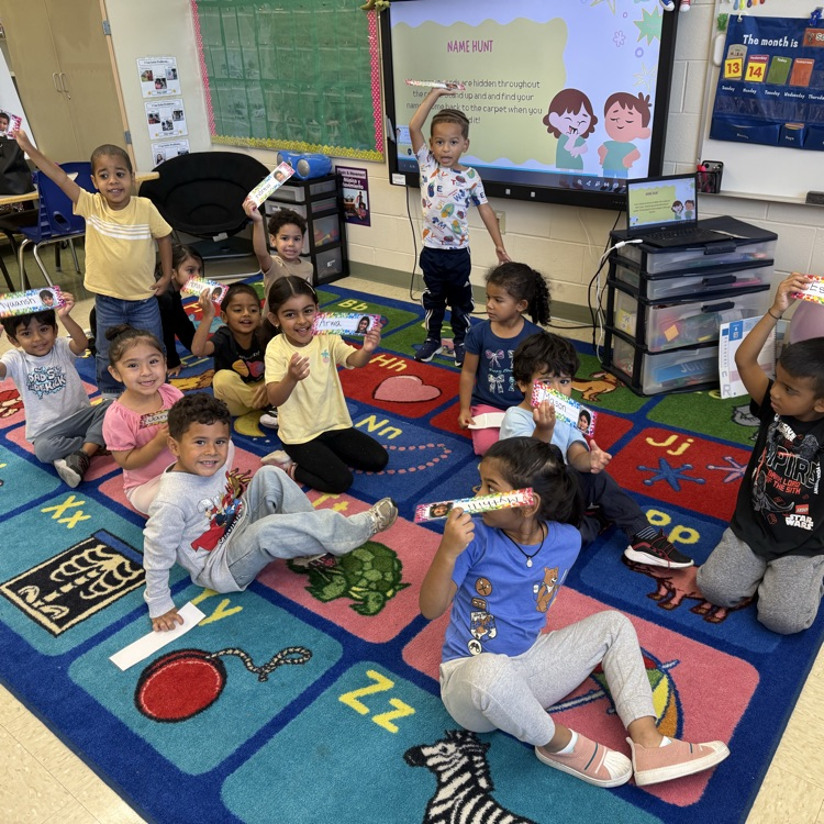 Students holding up signs from a classroom carpet