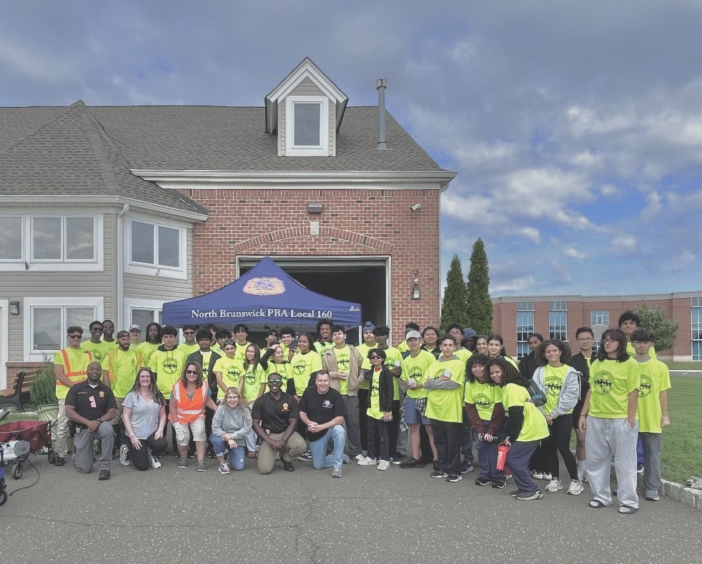 Student volunteers in bright green shirts cleaning up park