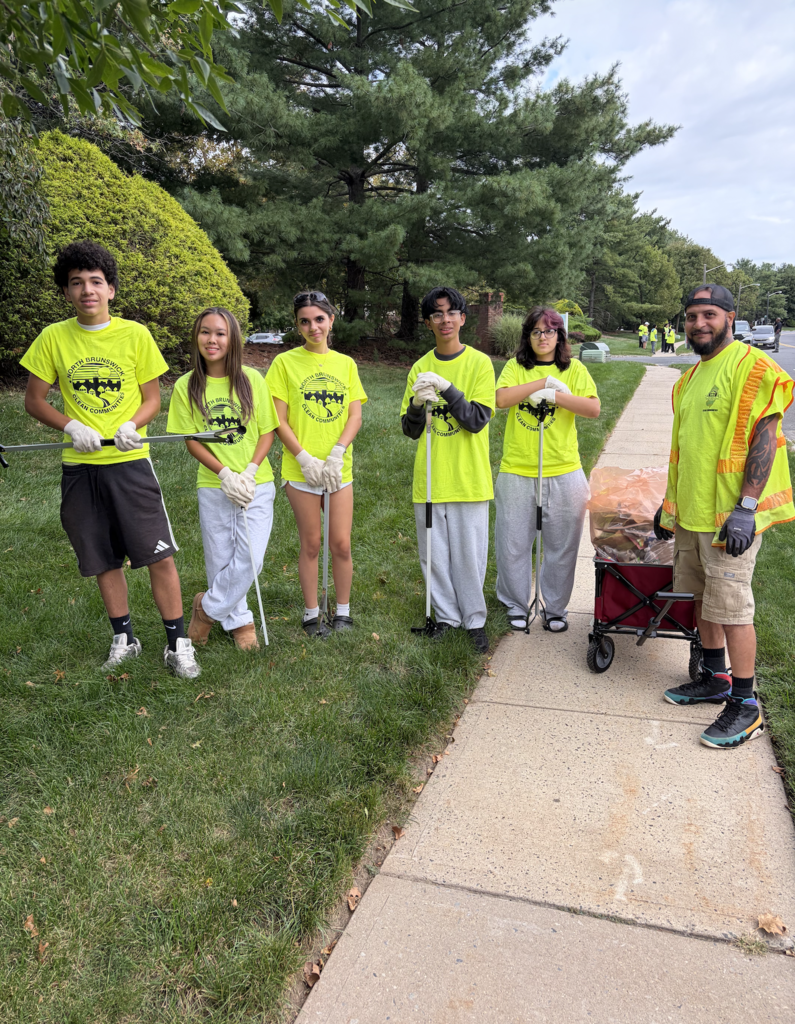Student volunteers in bright green shirts cleaning up park