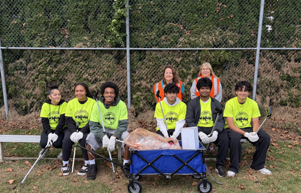 Student volunteers in bright green shirts cleaning up park