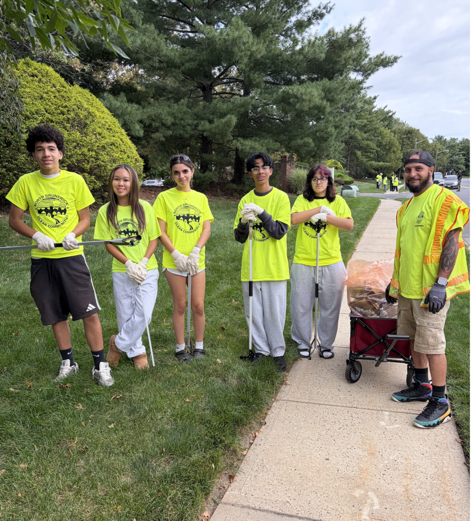 Student volunteers in bright green shirts cleaning up park
