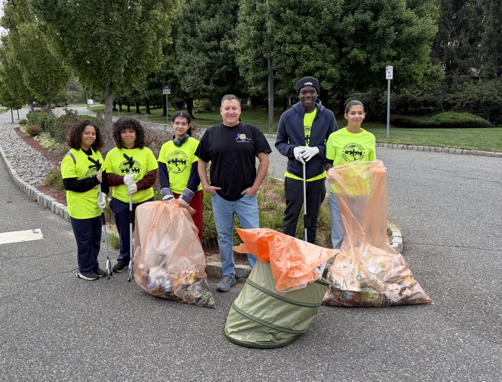 Student volunteers in bright green shirts cleaning up park