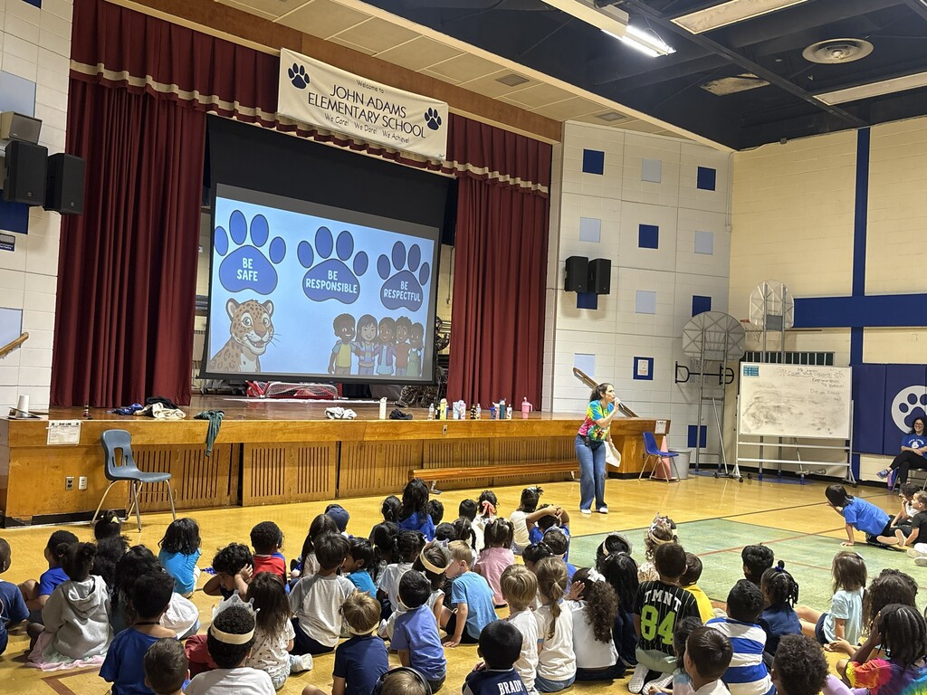 Students in gymnasium listening to a presenter