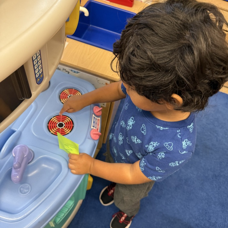 student pointing to part of a play stove