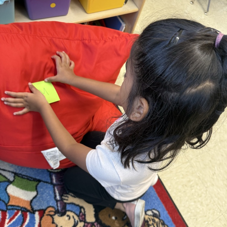 student putting a post it on a bean bag chair