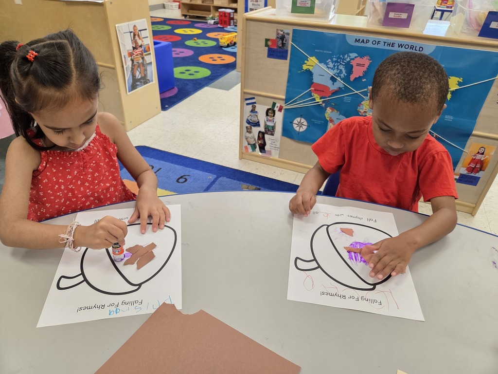 child gluing paper to an acorn paper