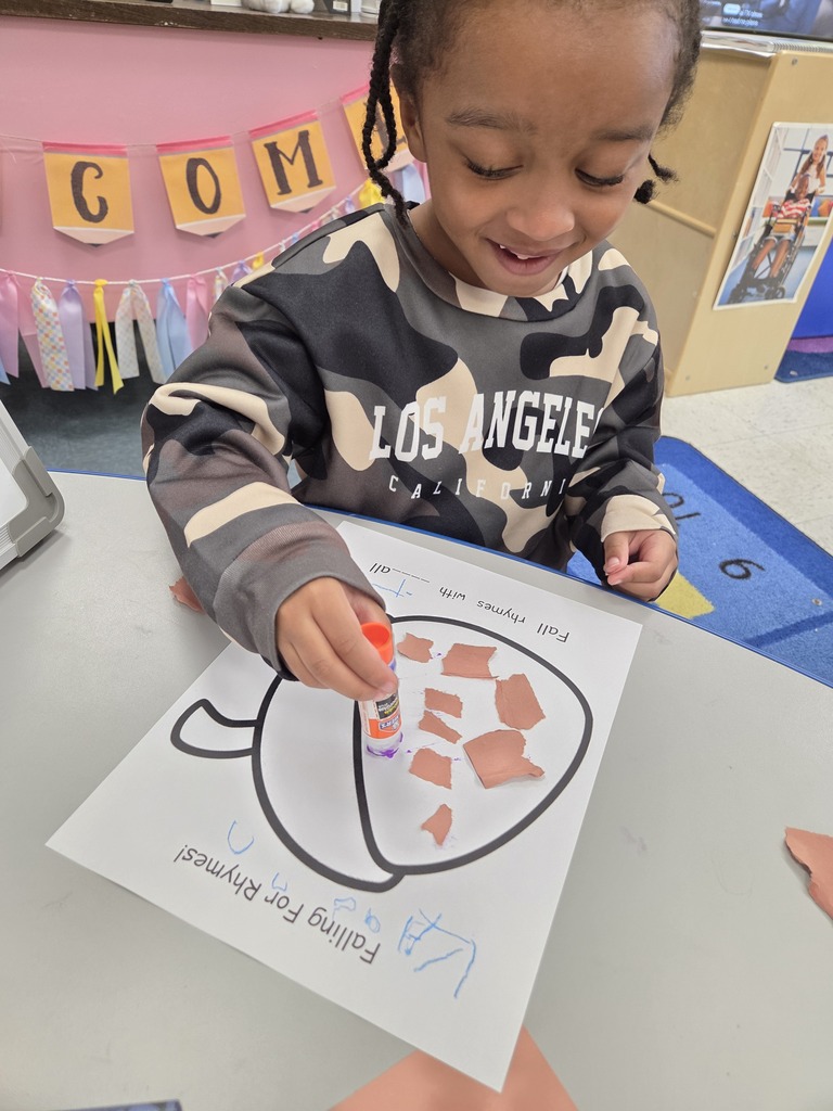 child gluing paper to an acorn paper