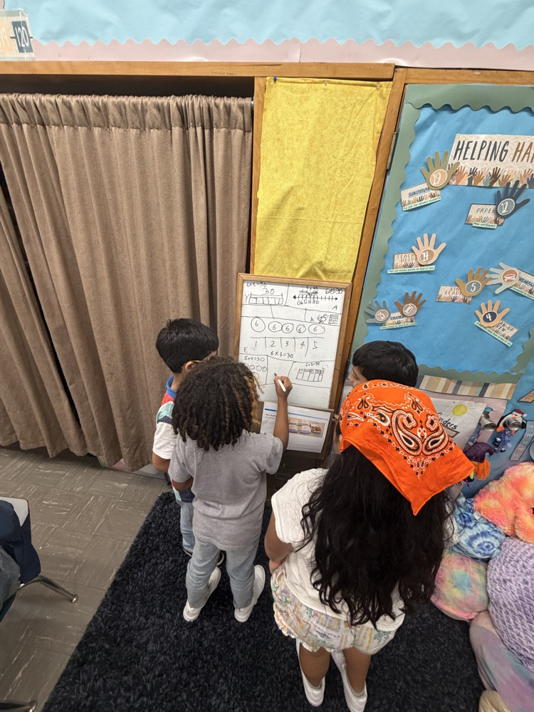 Students working together on easel as part of thinking classroom 