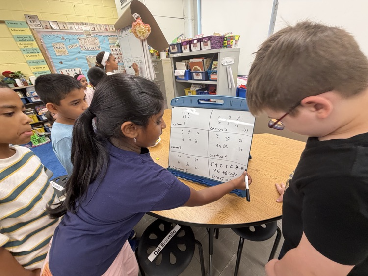 Students working together on easel as part of thinking classroom 
