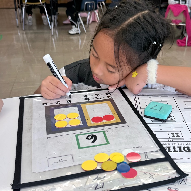Student practicing math with counters and marker