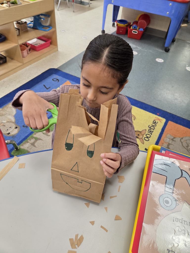 student cutting paper bag into monsters
