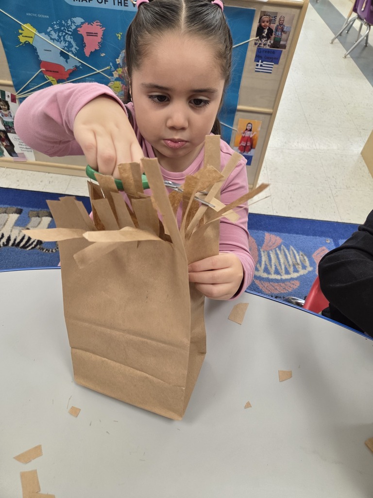 student cutting paper bag into monsters