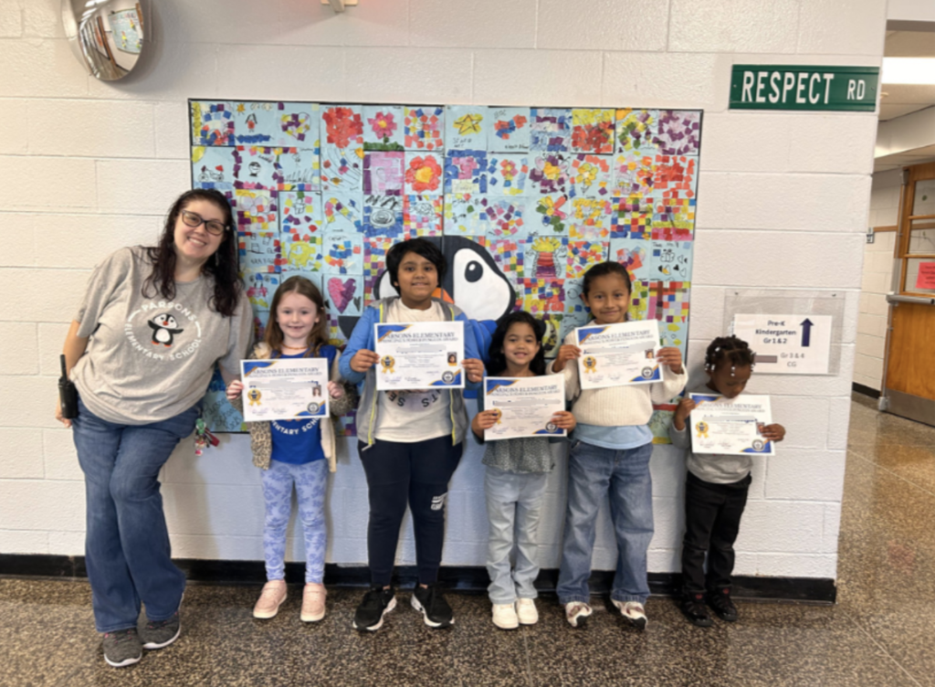 Principal standing with group of students with certificates