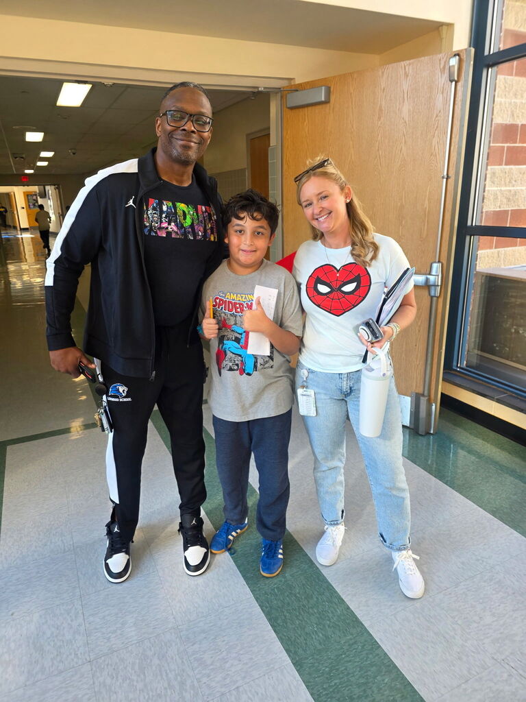 Staff and student posing together in hallway