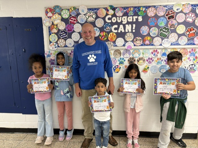 Principal standing with group of students with certificates called Friday Five 10/9/26