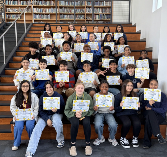 Students holding certificates in bleachers