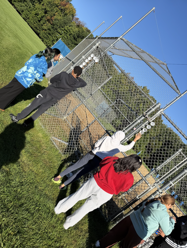Students placing cups into chainlink fence