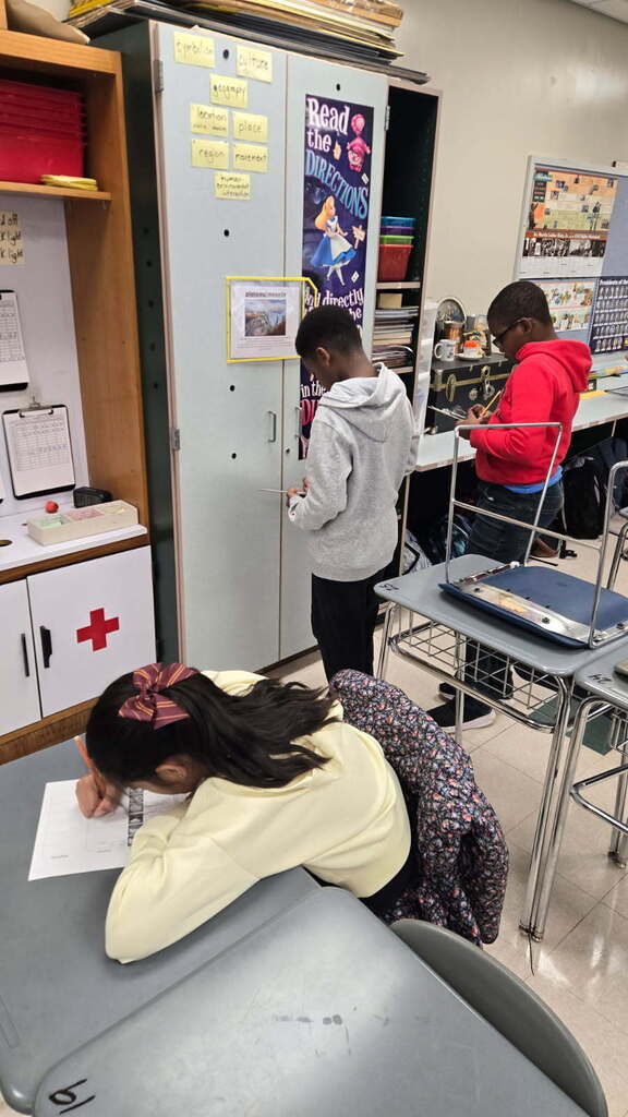 Students moving around the room defining landforms and Waterways during independent work.
