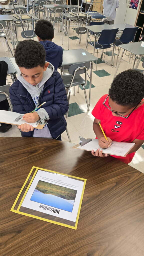 Two students recording the definition of a hill at one station.
