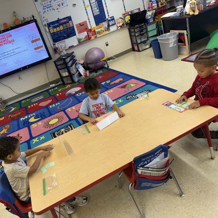 Students practicing with small letter cards at a table