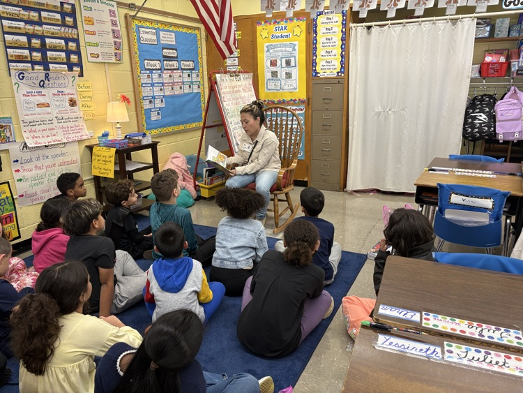 Guest reader reading to a class sitting on the carpet