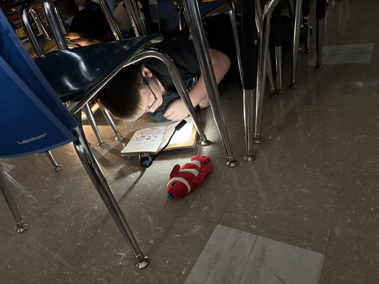 Student reading book with flashlight
