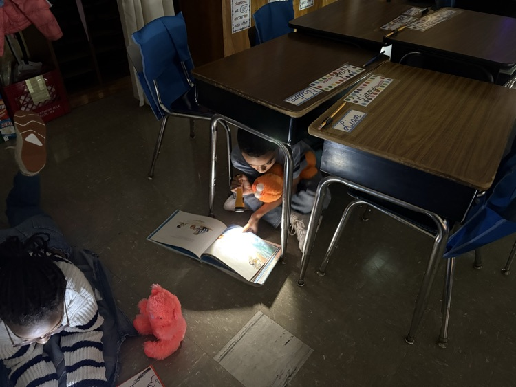 Student reading book with flashlight