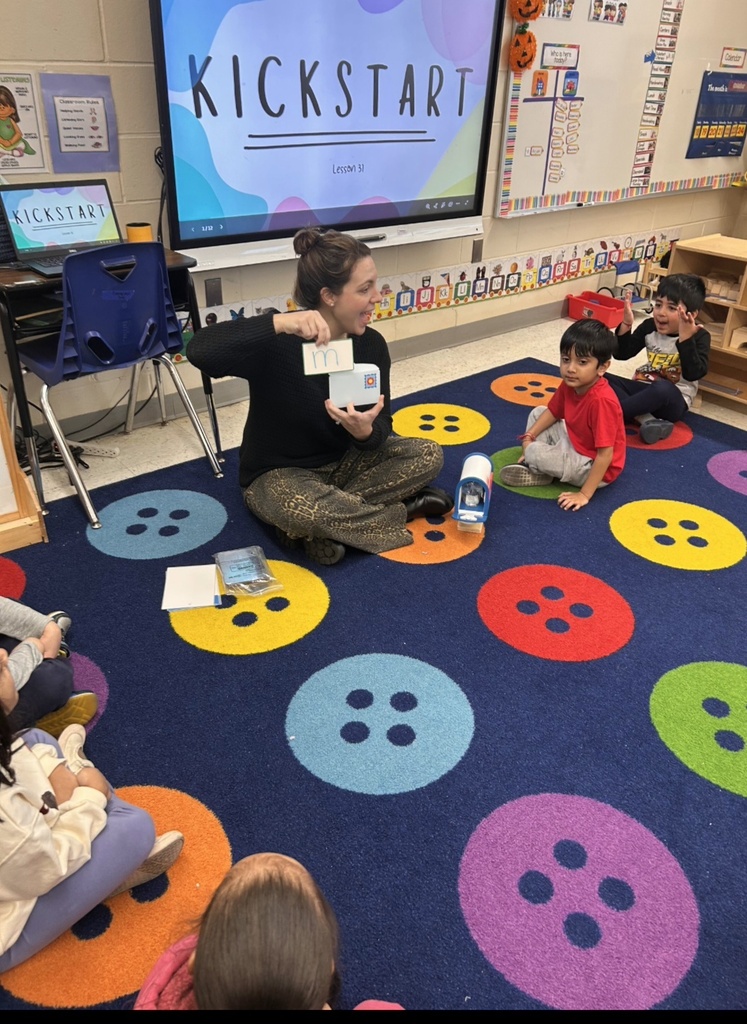 Students sitting on classroom carpet around teacher