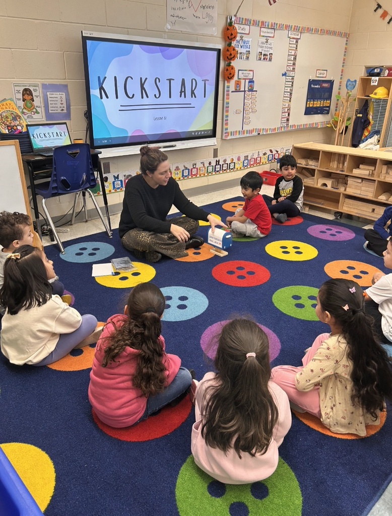 Students sitting on classroom carpet around teacher
