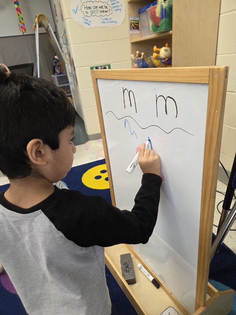 student writing the letter M on whiteboard