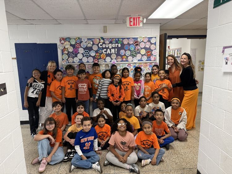 Group photo of students with teachers all wearing orange