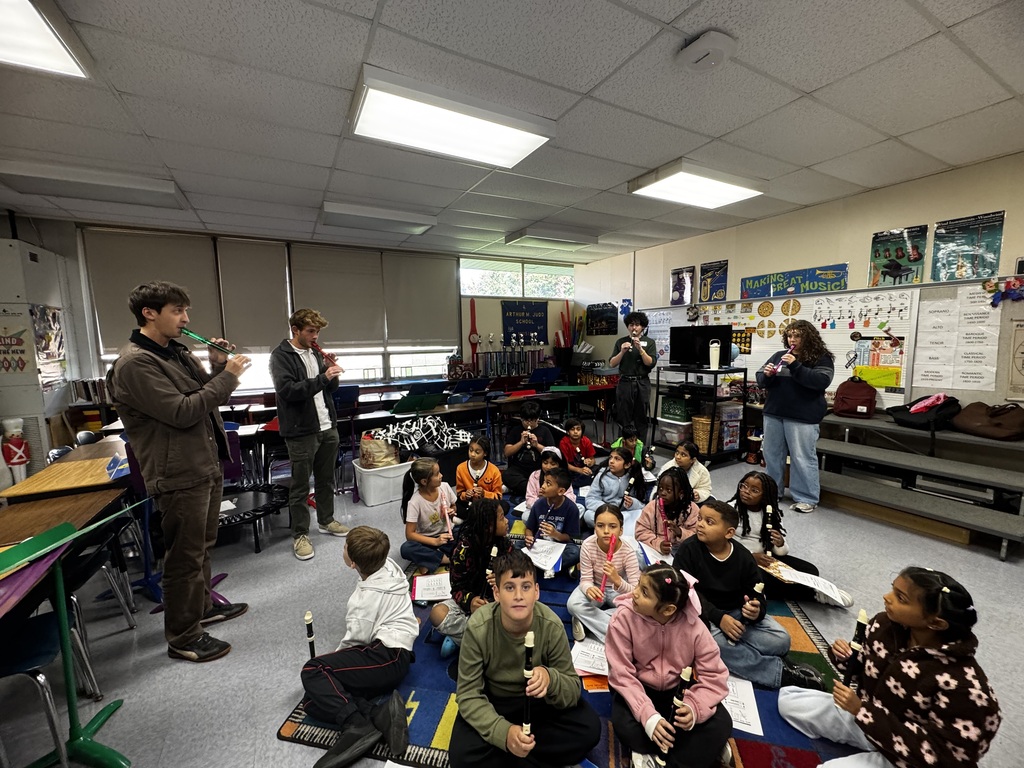 Students playing recorders sitting on the floor 