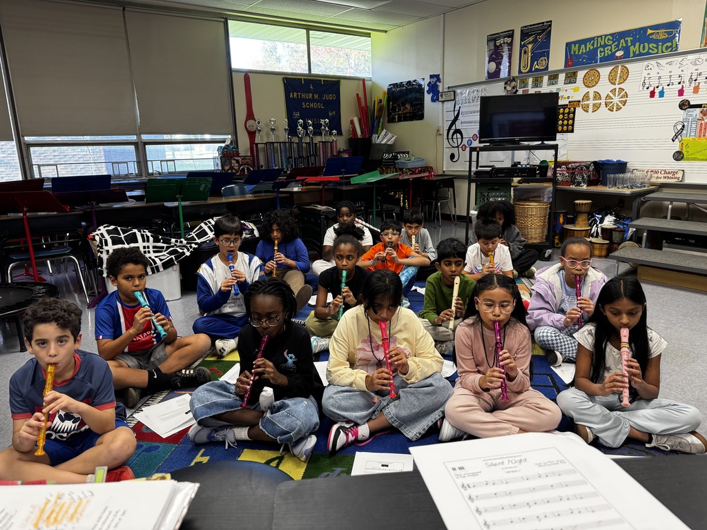 Students playing recorders sitting on the floor 