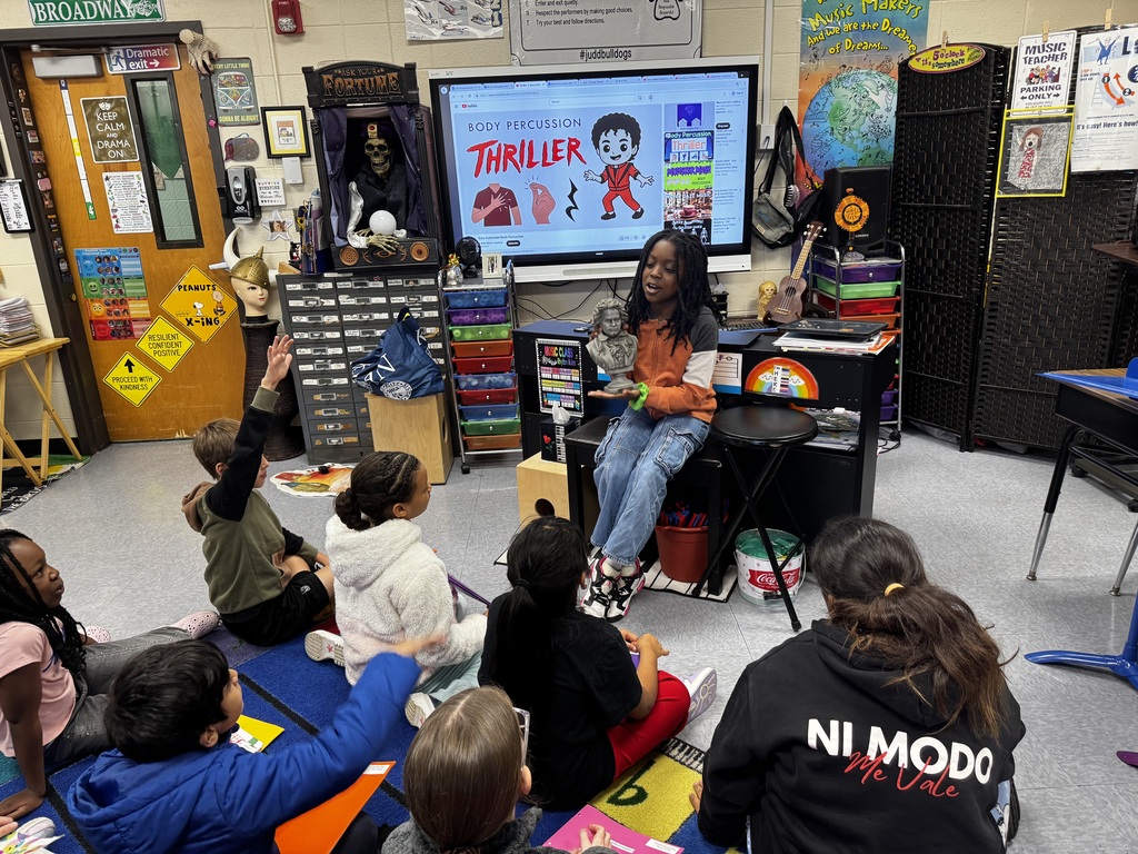 Students playing recorders sitting on the floor 