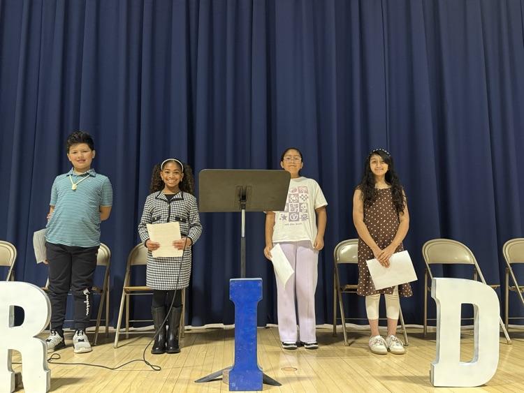 Students standing on stage with speeches in their hands