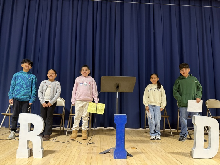 Students standing on stage with speeches in their hands