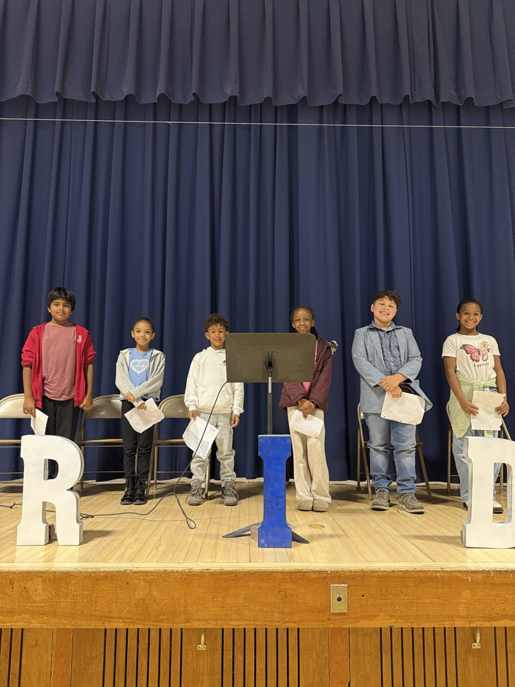 Students standing on stage with speeches in their hands