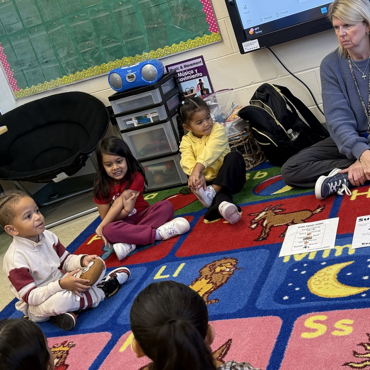 Students sitting on classroom carpet around teacher