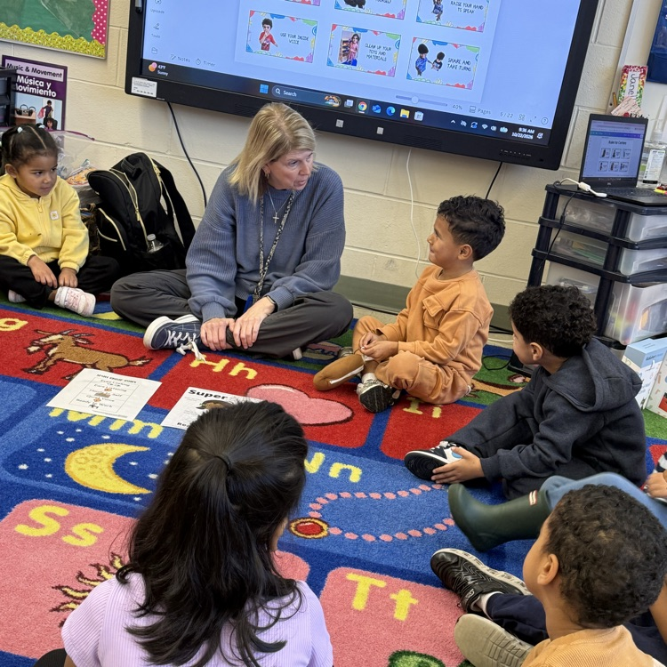 Students sitting on classroom carpet around teacher