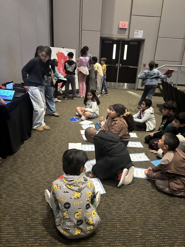 Students sitting of floor listening to a table presentation