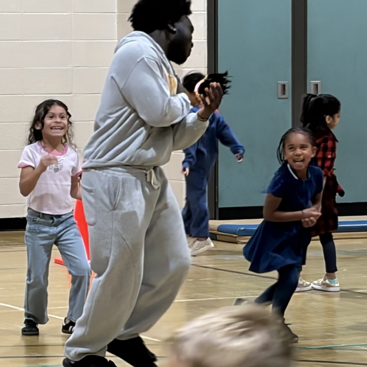 High school student playing in gym with little kids